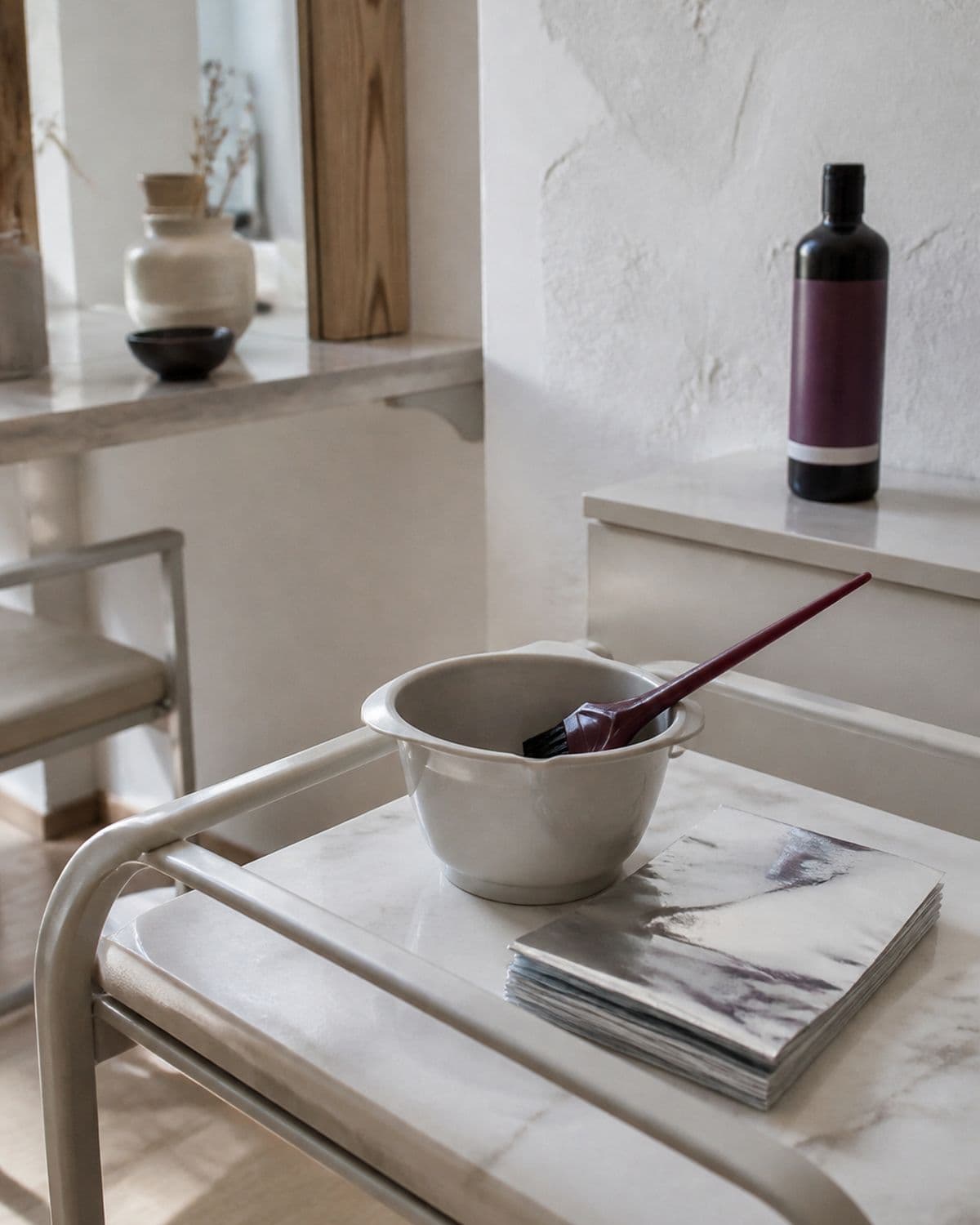A colour bowl and brush beside stacked foils on a marble trolley